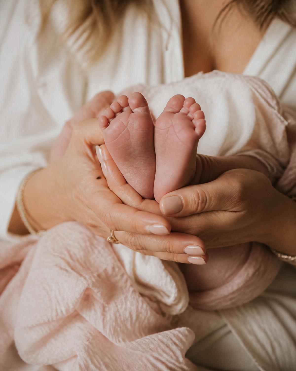 Mains d'une maman berçant les pieds de son nouveau-né