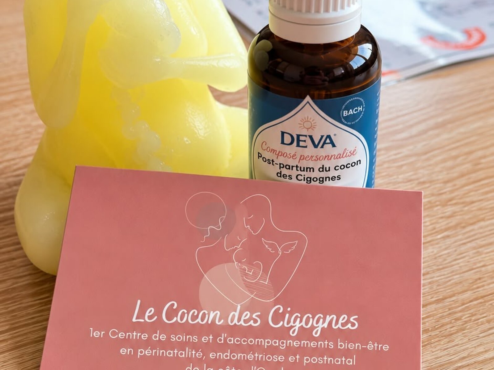Flacon compte-gouttes du composé personnalisé de Fleurs de Bach post-partum, posé à côté de la carte du Cocon des Cigognes